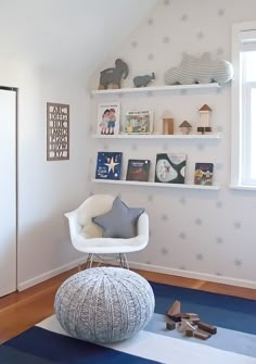 a white chair sitting on top of a blue rug in a room next to a window