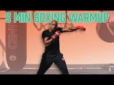 a man in black shirt and red boxing gloves standing next to a wall with the words 5 min boxing warmup on it