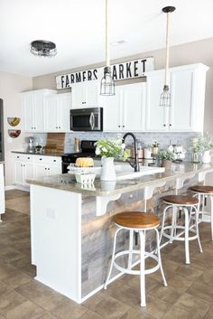 a kitchen with white cabinets and wooden stools next to an island in the middle