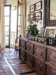 a large wooden dresser sitting in front of a window next to a mirror and potted plant