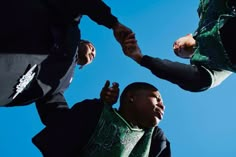 three people holding hands in front of a blue sky