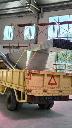 a yellow dump truck parked inside of a building with lots of scaffolding on it's sides