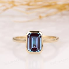 a ring with an emerald colored stone in the center on a white tablecloth background