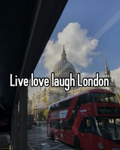 a red double decker bus driving down a street next to a tall building with the words live love laugh london on it