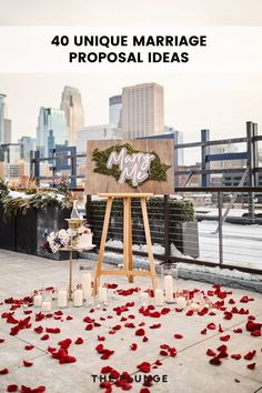 a wooden easel with red petals on the ground in front of a cityscape