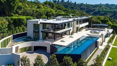 an aerial view of a house with a swimming pool in the foreground and lush green hillside behind it