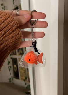 a hand holding a keychain with a fish in it's pouch hanging from the side