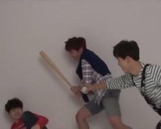 three young boys are playing baseball on the wall and one boy is holding a bat