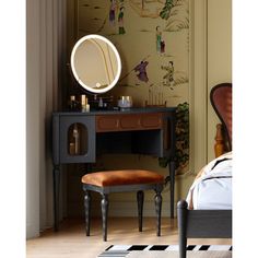 a dressing table with a mirror and stool in front of a wallpapered room