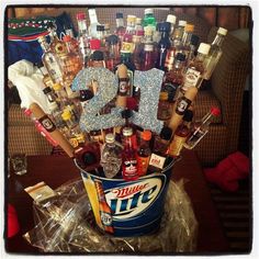 a bucket filled with lots of liquor bottles and condiments sitting on top of a table