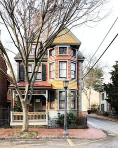 an old victorian style house on the corner of a street with trees in front of it