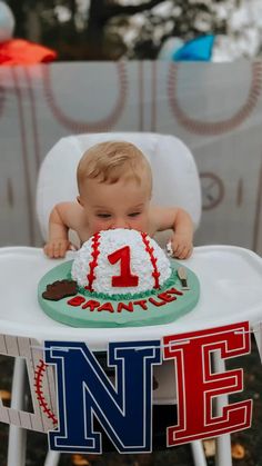 a baby sitting in a high chair with a baseball cake