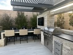 an outdoor kitchen with grill and dining table