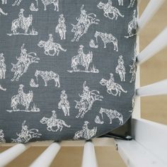 a close up of a pillow with horses and riders on it, sitting on a chair