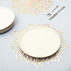 a table set with plates, silverware and gold leaf napkins on top of it