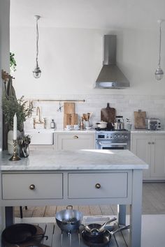 a kitchen with white cabinets and an island in the middle is filled with pots and pans