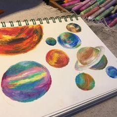 a spiral notebook with colored crayons on it and an image of the planets