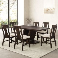 a dining room table with chairs and a rug in front of the table on carpeted floor