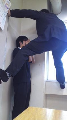 two men standing next to each other near a window