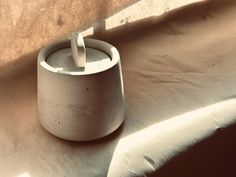 a white cup sitting on top of a table next to a window with a toothbrush in it