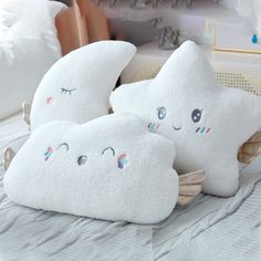 three white pillows sitting on top of a bed next to a pillow with eyes and eyelashes