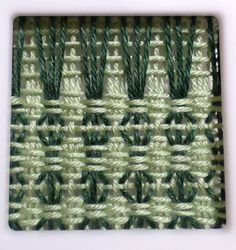 an image of green and white weaving on a piece of cloth or material that looks like woven fabric