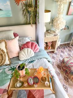 a bed with colorful pillows on top of it next to a tray filled with plants