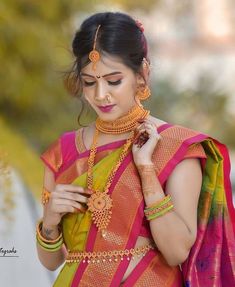 a woman in an orange and pink saree is looking down at her cell phone