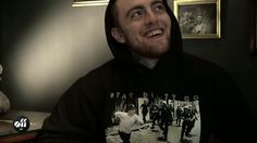 a man in a black hoodie is smiling and looking at the camera with other people around him