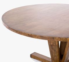 a round wooden table sitting on top of a white floor