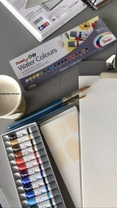 an assortment of watercolors and paper on a table