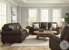 a living room with couches, chairs and a coffee table in front of two windows