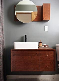 a bathroom with a sink, mirror and wooden cabinet in front of the shower curtain