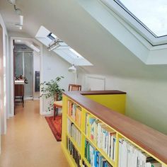 a room with a bookshelf filled with lots of books under a skylight