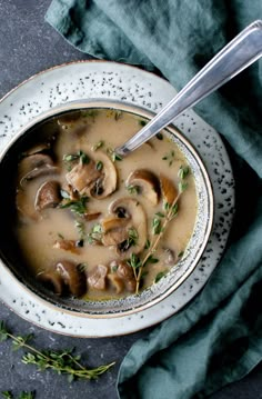 a bowl of soup with mushrooms and parsley in it on top of a blue towel