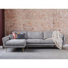 a grey couch sitting in front of a brick wall