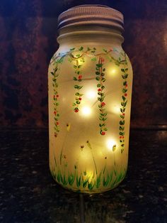 a mason jar with lights in the shape of flowers and leaves on it sitting on a table