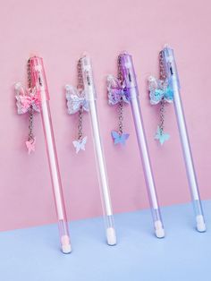 three different colored pens with bows on them are lined up next to each other against a pink and blue background