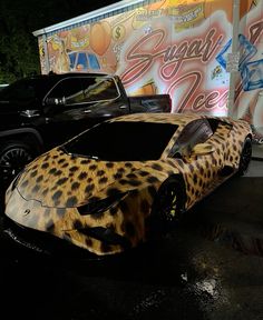 an animal print car is parked in front of a truck