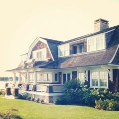 a large white house sitting on top of a lush green field next to a body of water