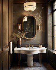 a bathroom with a sink, mirror and lights hanging from the ceiling over it's marble countertop