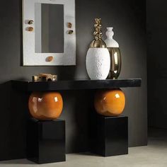 two orange vases sitting on top of a black table in front of a mirror