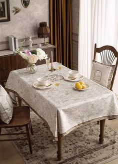 a dining room table with two plates on it and flowers in vases next to the table