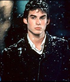 a young man standing in the snow wearing a black jacket