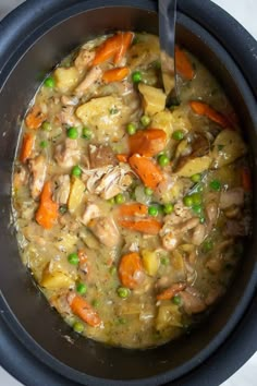 a bowl filled with chicken and vegetables on top of a table next to a spoon