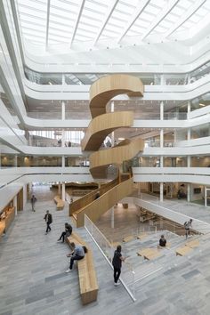 people are sitting on benches in the middle of a large building with stairs leading up to it