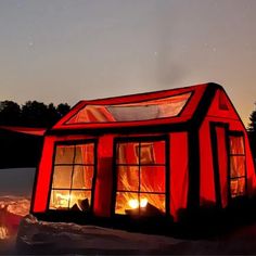 a small red building sitting on top of snow covered ground next to trees and night sky