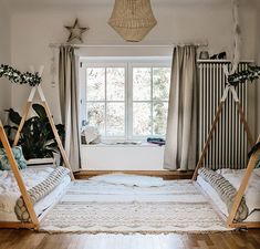 two beds in a room with white walls and wood flooring, one is made up to