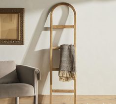 a chair sitting in front of a white wall next to a wooden shelf with a towel on it