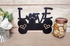 a wooden sign that says love with a dog bone next to some cookies in a jar